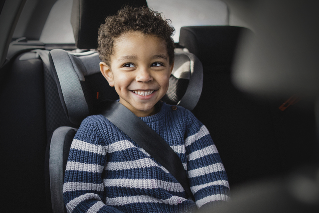 Enfant souriant en sécurité dans un VTC à Toulouse avec ceinture de sécurité