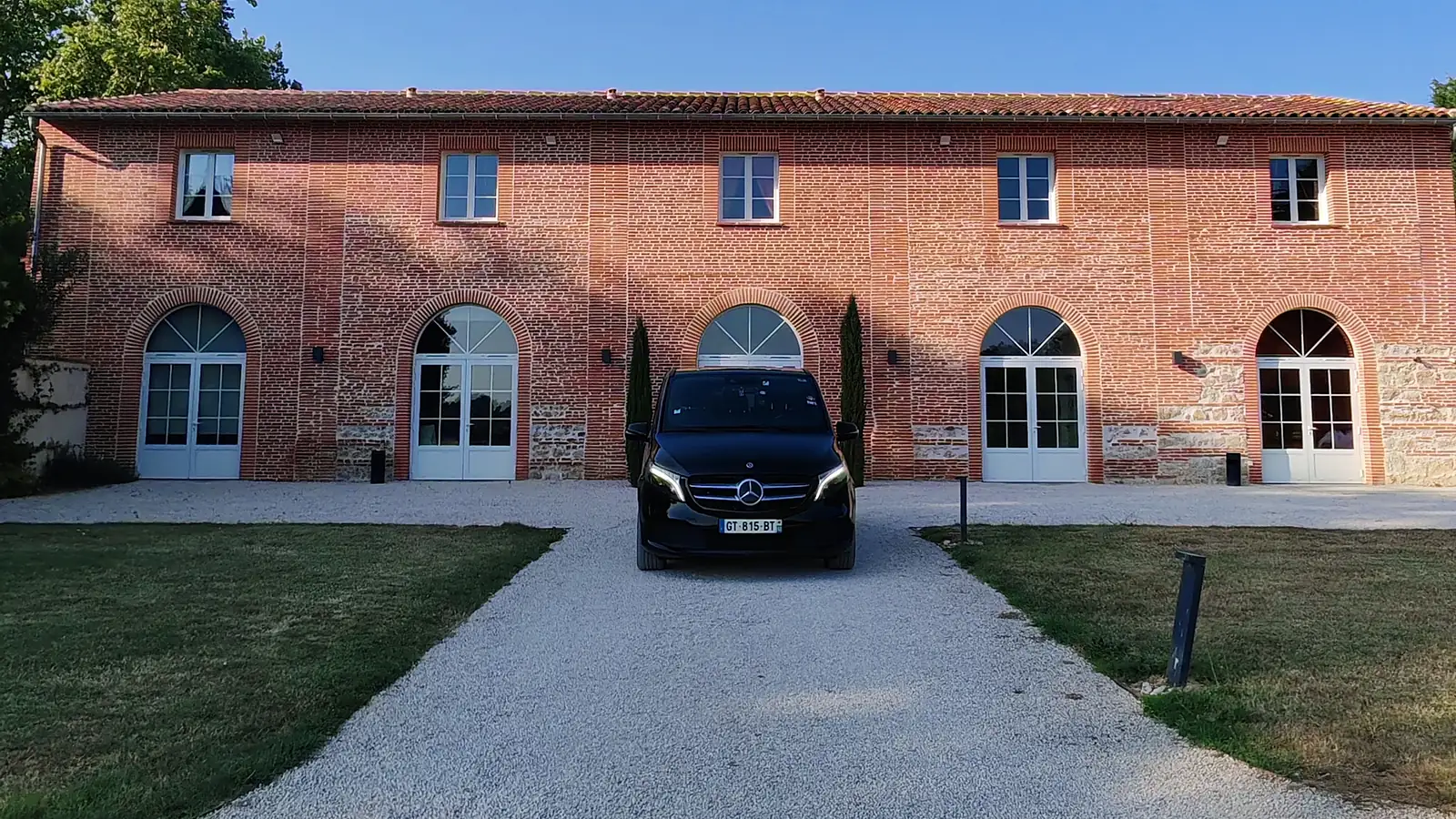 Navette mariage Toulouse — van Mercedes noir avec chauffeur devant un domaine de réception, transport des invités entre la cérémonie et la soirée